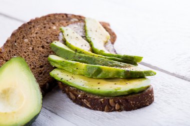 Koyu siyah ekmek üzerinde avokado sandviç.