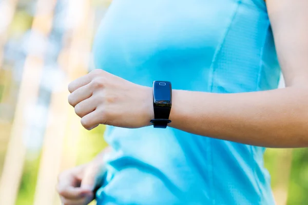 Brazos de mujer corredora con monitor de frecuencia cardíaca para correr en el bosque . — Foto de Stock