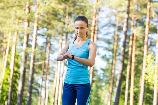 Mujer corredora con monitor de frecuencia cardíaca para correr en el bosque . — Foto de Stock