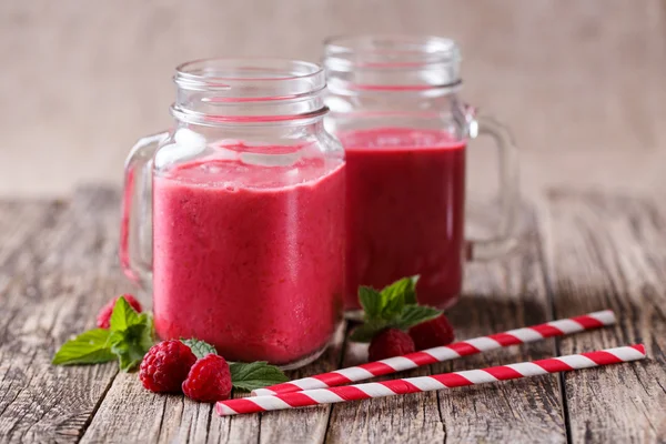 Tasty raspberry smoothie in glass jar on wooden table. — Stock Photo, Image