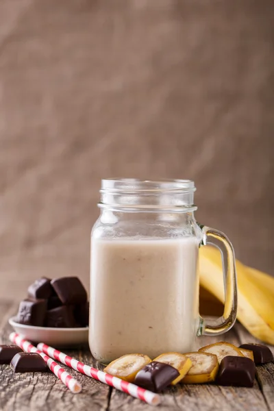 Banana smoothie  with chocolate in glass jar with drinking straw — Stock Photo, Image