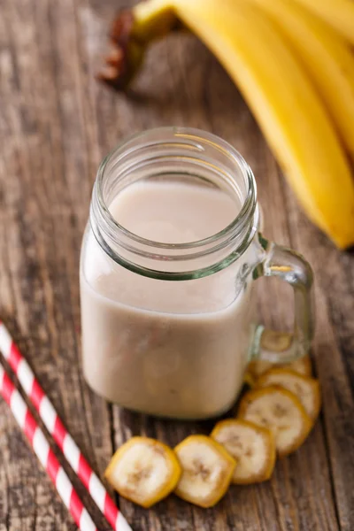 Healthy banana smoothie in glass jar with bananas on wooden tabl — Stock Photo, Image
