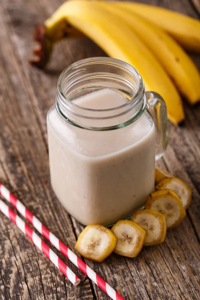 Batido de plátano saludable en frasco de vidrio con plátanos en tabla de madera —  Fotos de Stock