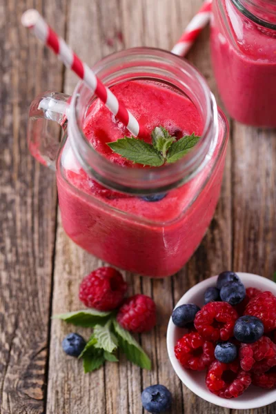 Здоровый смузи с малиной, ягодами на тарелках и питьевой — стоковое фото