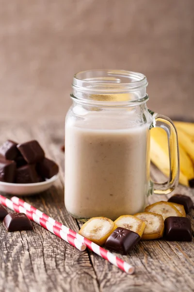 Banana smoothie  with chocolate in glass jar with drinking straw — Stock Photo, Image