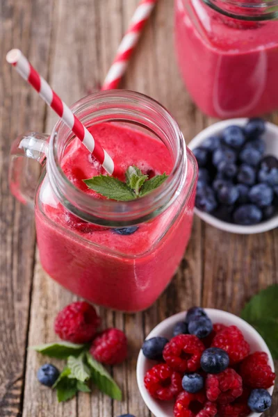 Здоровый смузи с малиной, ягодами на тарелках и питьевой — стоковое фото