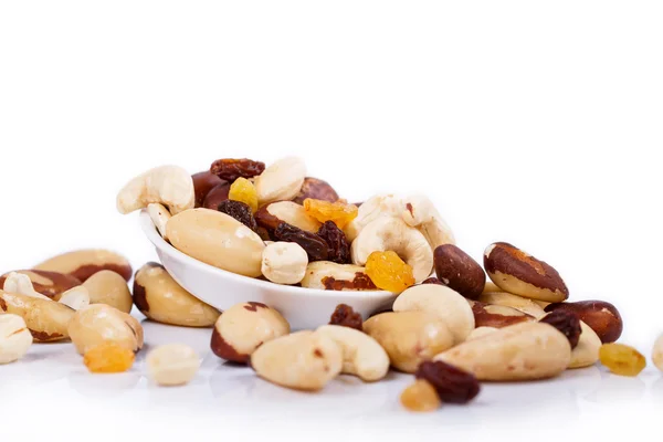 Mixed nuts and sultanas on a plate on a white background — Stock Photo, Image