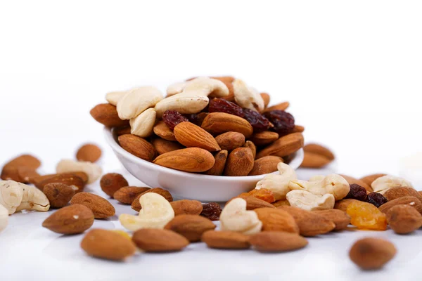 Mixed nuts and sultanas on a plate on a white background — Stock Photo, Image