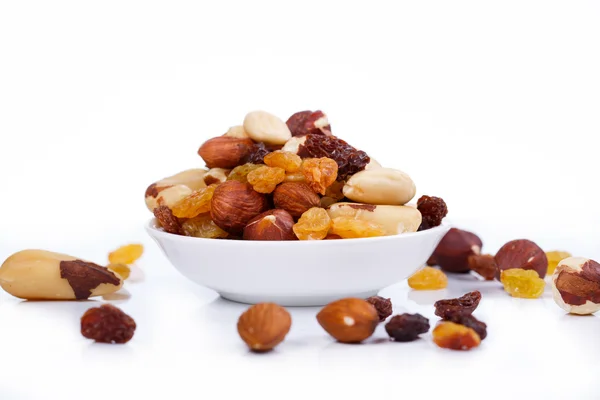 Gemischte Nüsse und Sultaninen auf einem Teller auf weißem Hintergrund — Stockfoto