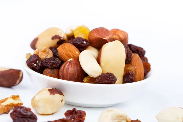 Mixed nuts and sultanas on a plate on a white background — Stock Photo, Image