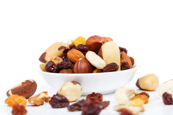 Mixed nuts and sultanas on a plate on a white background — Stock Photo, Image