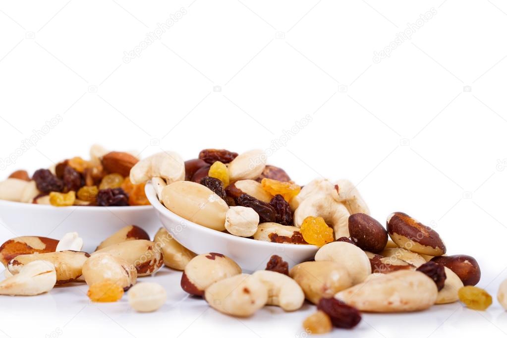 Mixed nuts and sultanas on a plate on a white background