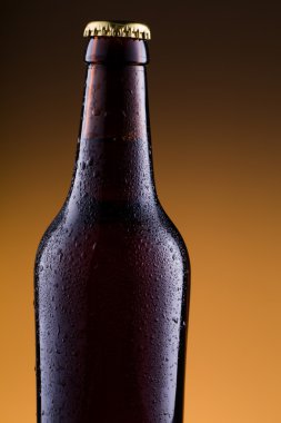 Altın arka planda bira şişesiyle su damlaları.