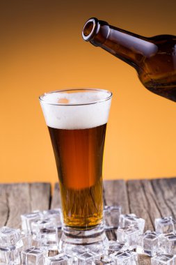 Bir cam ve buzun altın arka plan içinde bira şişesiyle.