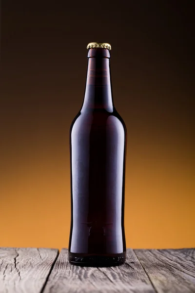 Beer bottle without water drops in golden background.