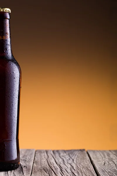 Beer bottle with water drops in golden background. — Stock Photo, Image