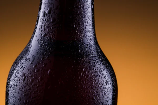 Beer bottle with water drops in golden background. — Stock Photo, Image