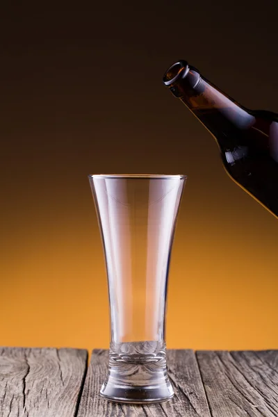 Beer bottle with a glass in golden background. — Stock Photo, Image