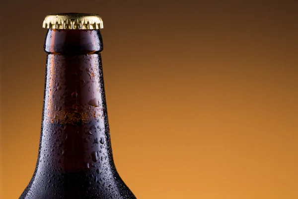 Beer bottle with water drops in golden background. — Stock Photo, Image