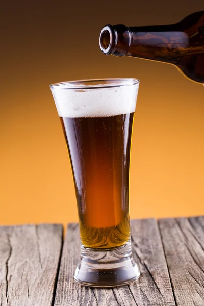 Beer bottle with a glass in golden background. — Stock Photo, Image