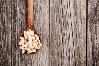 Ahşap arka plan üzerine bir kaşık kaşu fındık.