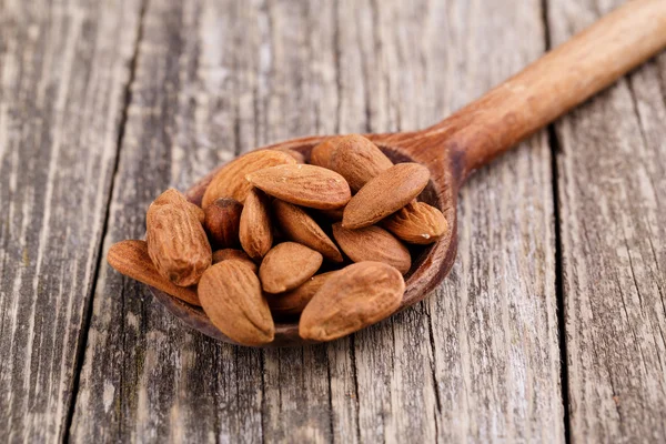 Almendras sobre una cuchara sobre un fondo de madera . —  Fotos de Stock