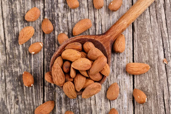 Almendras sobre una cuchara de madera . — Foto de Stock