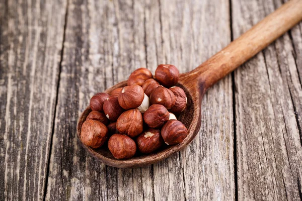 Hazelnuts on a spoon on wooden background. — Stock Photo, Image