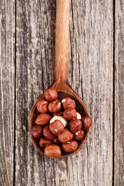 Haselnüsse auf einem Löffel auf Holzgrund. — Stockfoto