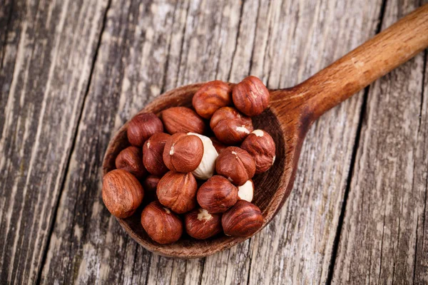 Hazelnuts on a spoon on wooden background. — Stock Photo, Image