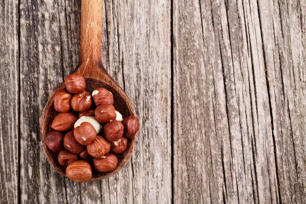 Hazelnuts on a spoon on wooden background. — Stock Photo, Image