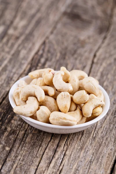 Cashew nuts on a plate on wooden background. — Stock Photo, Image