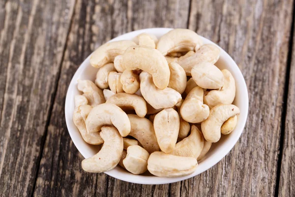 Cashew nuts on a plate on wooden background. — Stock Photo, Image