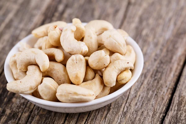 Cashew nuts on a plate on wooden background. — Stock Photo, Image