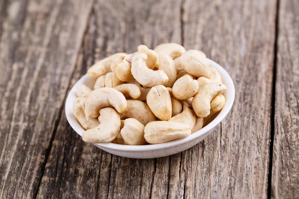 Cashew nuts on a plate on wooden background. — Stock Photo, Image