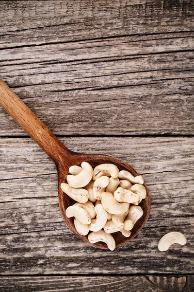 Cashew nuts on a spoon on wooden background. — Stock Photo, Image