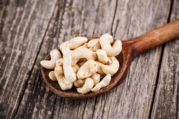 Cashew nuts on a spoon on wooden background. — Stock Photo, Image