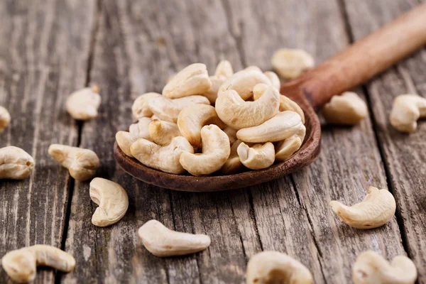 Cashew nuts on a spoon on wooden background. — Stock Photo, Image