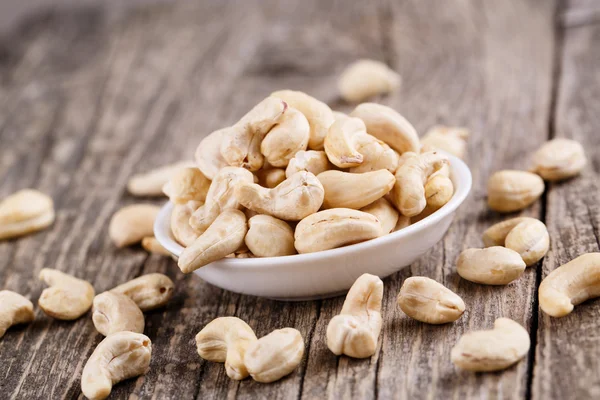 Cashew nuts on a plate on wooden background. — Stock Photo, Image