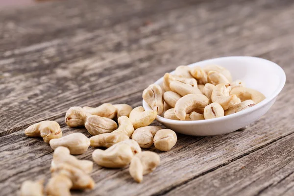 Cashew nuts on a plate on wooden background. — Stock Photo, Image