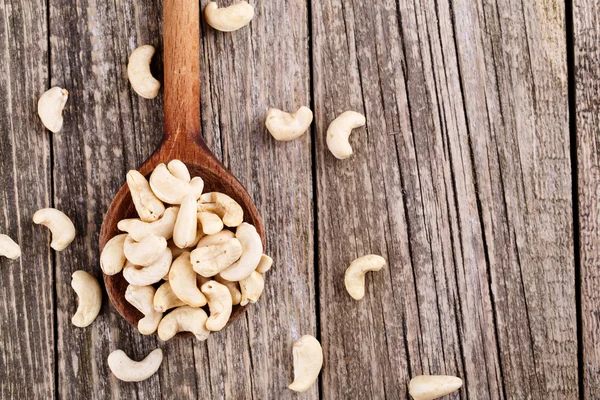 Cashew nuts on a spoon on wooden background. — Stock Photo, Image