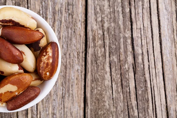 Brazil nuts on a plate on wooden background. — Stock Photo, Image