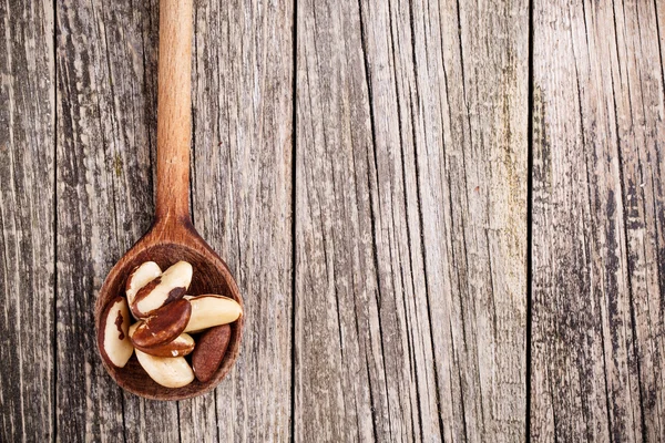 Brazil nuts on a spoon on wooden background. — Stock Photo, Image