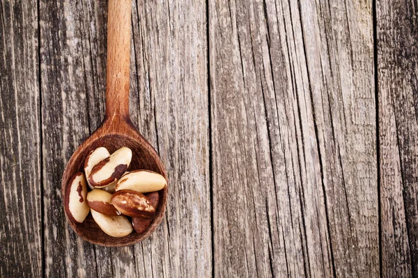 Brazil nuts on a spoon on wooden background. — Stock Photo, Image