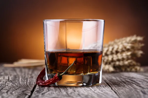 Glas Whisky mit Eis und Weizen auf einem Holztisch. — Stockfoto