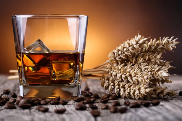 Un vaso de whisky con hielo y trigo sobre una mesa de madera . — Foto de Stock