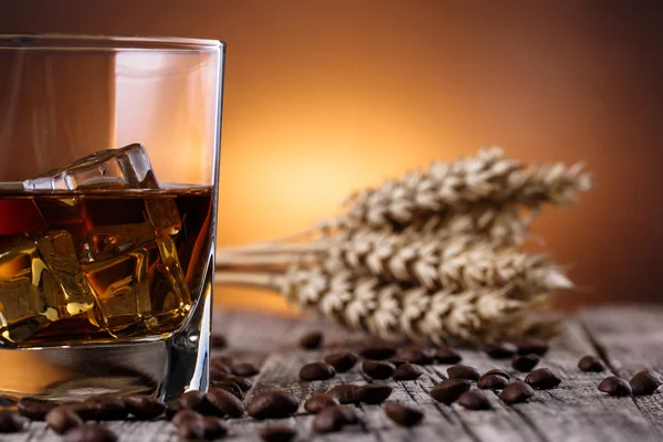 Un vaso de whisky con hielo y trigo sobre una mesa de madera . — Foto de Stock