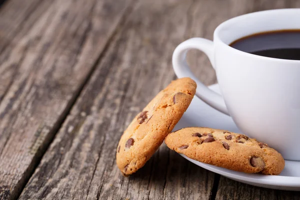 Tahta bir masada bir fincan kahve ve kurabiyeler..