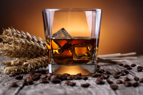 Bicchiere di whisky con ghiaccio e grano su un tavolo di legno . Immagini Stock Royalty Free