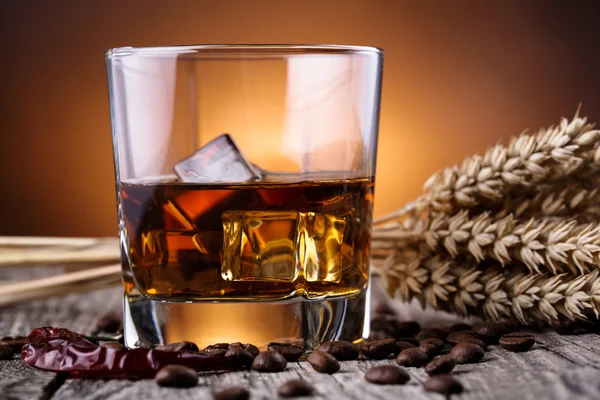 Un vaso de whisky con hielo y trigo sobre una mesa de madera . — Foto de Stock